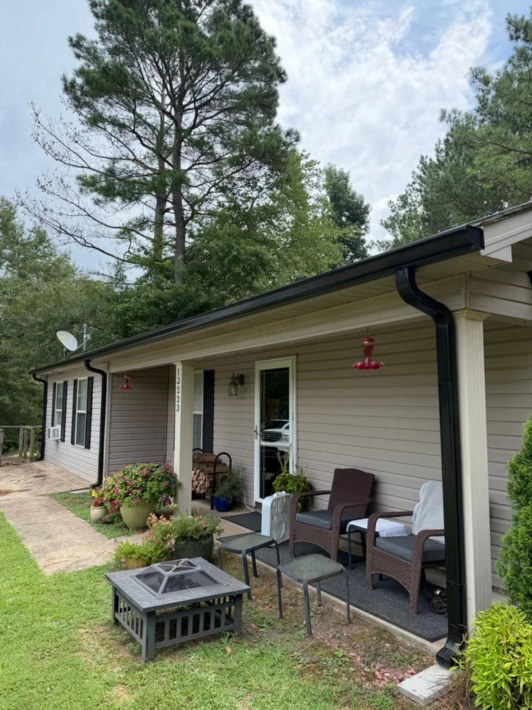 Black aluminum gutters and downspouts on residential home with white siding