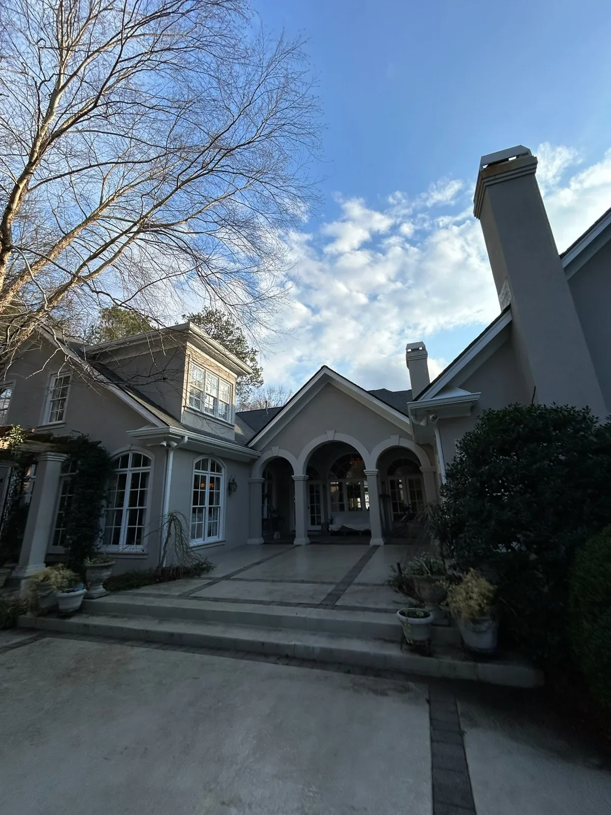 Dark seamless gutters and downspouts on white contemporary home with multiple roof peaks