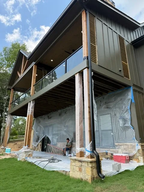 Metal siding home with wooden posts, deck framing, and protective sheeting during construction